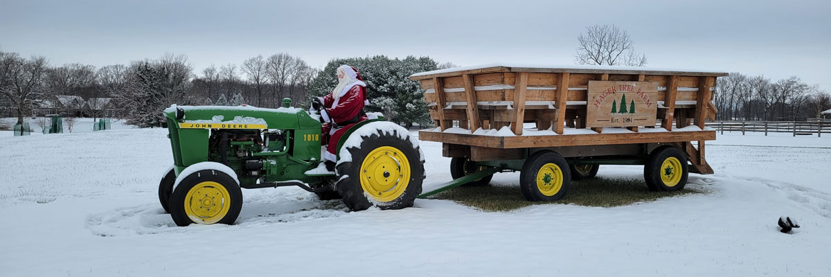 Santa Claus driving a tractor with a passenger wagon